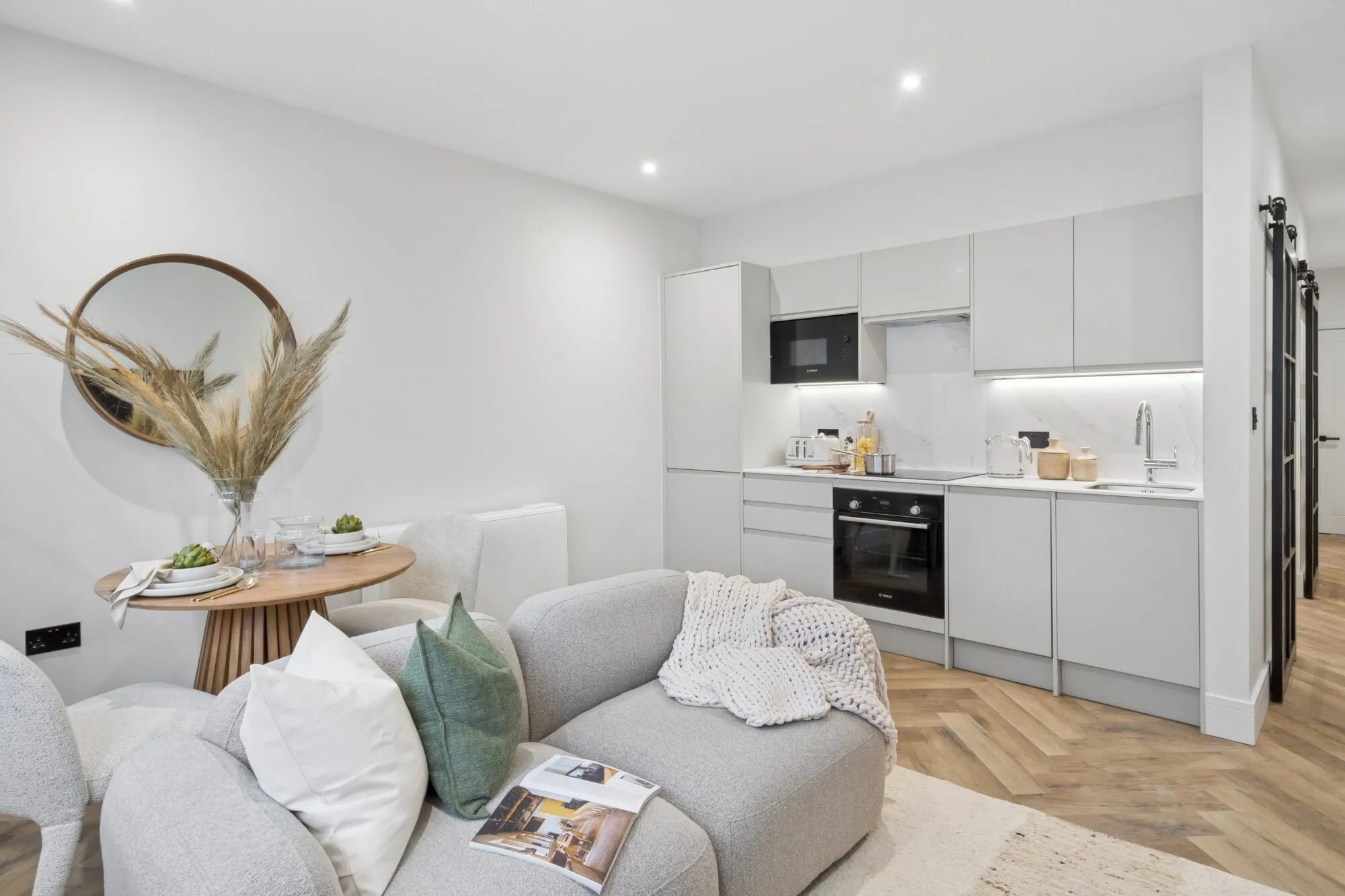 Open-plan living space in one of the new Manhattan apartments in Marlow, with a sofa, dining table and the kitchen beyond.